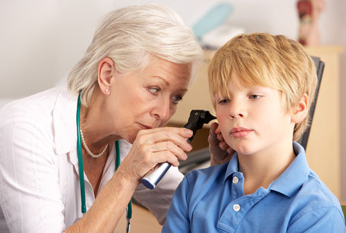 GP examining boys ear